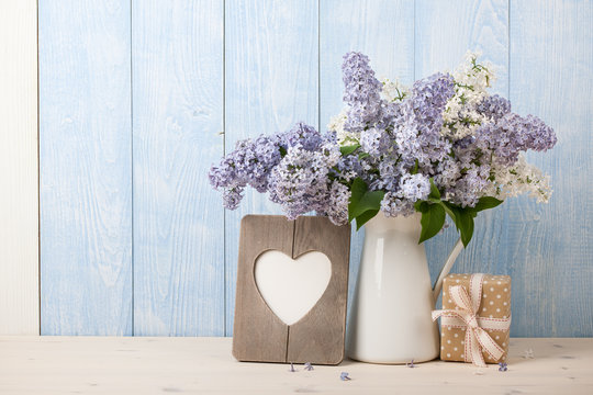 Lilac flowers in jug, gift box and heart shaped frame for greeting