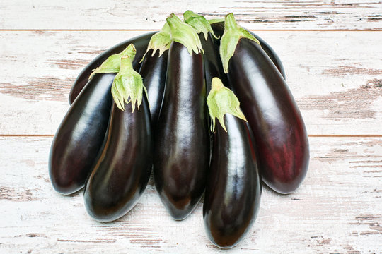  freshly picked eggplants on an old wooden surface