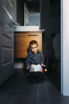 Portrait of boy defecating while sitting on potty seen through doorway at home