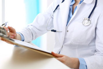 Female doctor filling up medical form on clipboard closeup. Healthcare, insurance and medicine concept