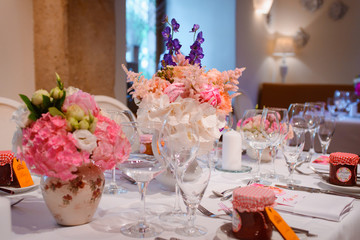 Dining table setting at Provence style, with candles, lavender, vintage crockery and cutlery, closeup. Beautiful wedding decoration with flowers pink violet purple white colors
