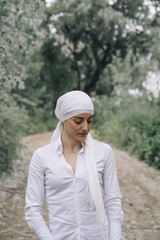 woman with white headscarf in the forest, has cancer