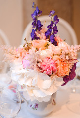 Dining table setting at Provence style, with candles, lavender, vintage crockery and cutlery, closeup. Beautiful wedding decoration with flowers pink violet purple white colors