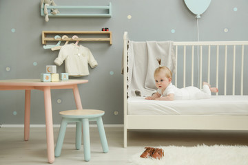 Adorable baby in the white outfit in the nursery