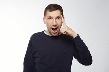 Dark haired man has brilliant idea. Smart European cheerful man with beard and mustache, raises index finger, has intriguing plan, opens mouth widely, isolated over white background with copy space.