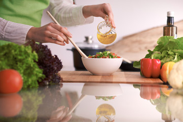 Close Up of human hands cooking vegetable salad in kitchen on the glass table with reflection. Healthy meal, and vegetarian food concept