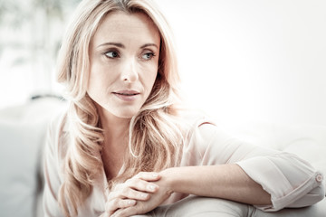 Have a rest. Calm pleasant pretty woman sitting on the sofa looking aside spending time at home.