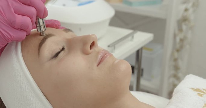 Beautiful woman is getting the diamond microdermabrasion and facial peeling procedure in beauty salon. Skincare and Health. 4k footage.