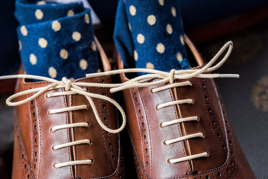 Men's leather new brown shoes closeup still life isolated with blue polka dot socks, shoelaces laces tied, wedding or interview preparation in room