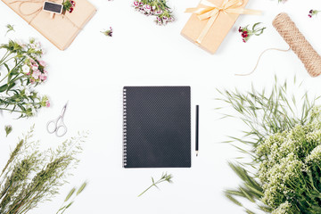 Black notebook among lush flowers and gifts