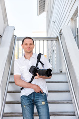 Young handsome attractive man hipster millennial photographer with camera in Seaside, Florida panhandle town, white beach architecture smiling