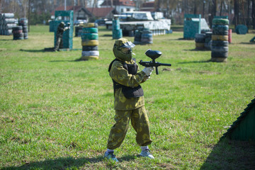 two teams of paintball players in camouflage form with masks, helmets, guns on the field in the summer. sport life concept