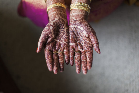 Cropped hands of bride showing henna tattoo at home