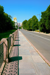 The direct fenced sidewalk and the road towards Catherine Palace in the summer solar morning