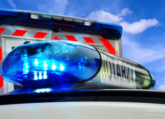 Teilansicht Feuerwehreinsatzfahrzeug mit Blaulicht und krankenwagen im Hintergrund. Notruf 112