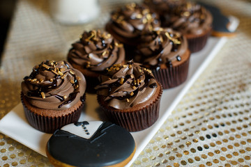 white rectangular plate with chocolate cakes.
chocolate cupcakes with cream  on the plate.