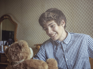 young happy teenager boy in checkered shirt with teddy bear
