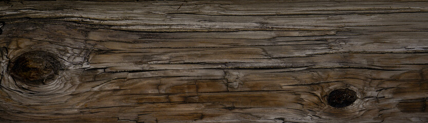 Old Dark rough wood floor or surface with splinters and knots. Square background with flooring or boards with wood grain. Old aged timber in a barn or old house.