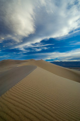 Fototapeta na wymiar Sand dunes and a cloudy sky create a dramatic landscape.