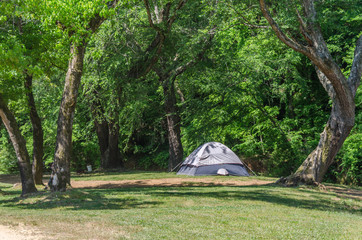 Campsite with tent in beautiful outdoor setting.  Spring, summer sunshine and trees.  Enjoy the relaxation and adventure of tent camping.