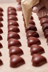 heart-shaped chocolates being decorated with a gloved hand