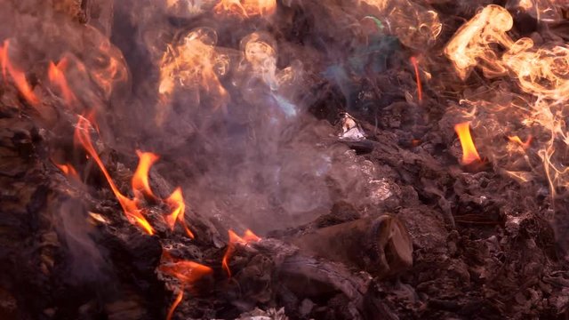 Slow motion fire burning garbage bag on sunrise dark backgorund. White smoke floating to air pollution and dangerous environment. Garbage is waste from comunity. It make green house effect of Earth.