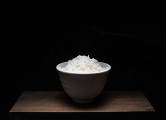 Bowl of rice on wood  black background, traditional food for South East Asia