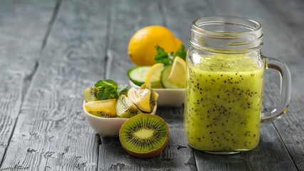 Mug with smoothies of kiwi, cucumber, lemon, parsley and mint on a table.