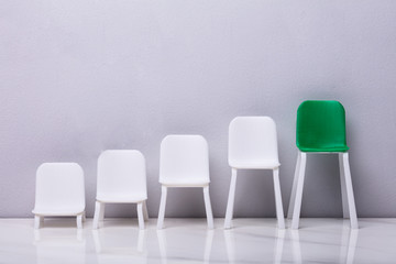 Increasing Scale Of White And Green Chairs In A Row