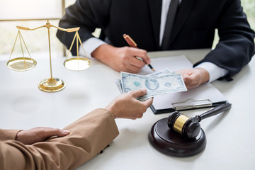 Bribery and corruption concept, bribe in the form of dollar bills, Businesswoman giving money to male lawyer while helps making deal to agreement a real estate contract and financial corporate