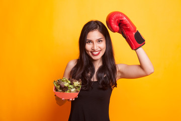 Young Asian woman with boxing glove and salad.