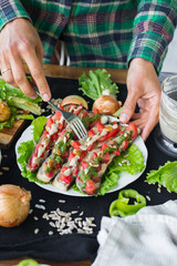 Woman hands holds plate with roasted baked eggplants slices with tomatoes, walnuts dressing, salad leaves and vegan sunflower seeds mayonnaise. Raw vegan vegetarian healthy food. Vegan lunch or dinner