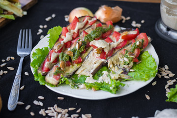 Roasted baked eggplants slices with tomatoes, walnuts dressing, salad leaves and vegan sunflower seeds mayonnaise. Raw vegan vegetarian healthy food. Vegan lunch or dinner