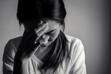 Depressed and stressed woman sitting on the floor alone head in hands in the dark room
