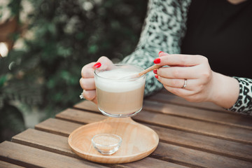 Closeup woman hand holding cup of coffee in cafe