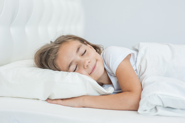 Smiling little girl sleeping on the bed. Space for text