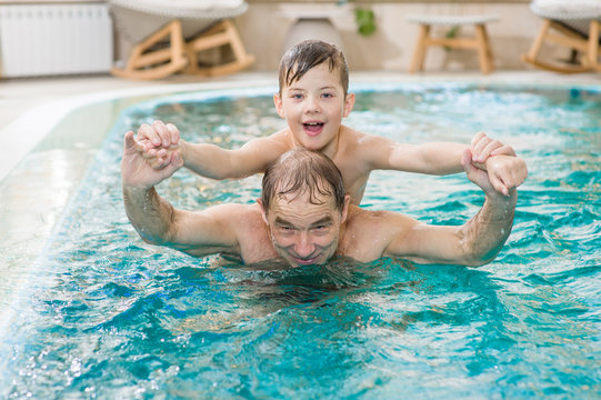 grandfather having fun with his grandson in the pool