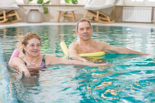 senior woman and man doing aqua fitness with swim noodles