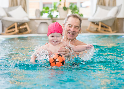 grandpa fun playing ball with granddaughter in the pool