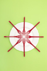 Still Life with plastic forks and a plate on a green background, for decoration, for text design, for template
