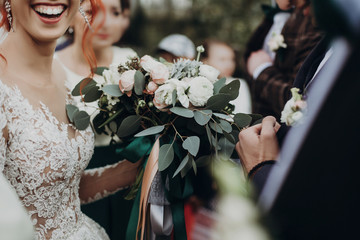 stylish happy bride holding modern bouquet and smiling. emotional moment. rustic wedding morning....