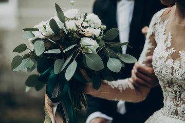 stylish happy bride holding modern bouquet with roses and eucalyptus. flowers close up. romantic...