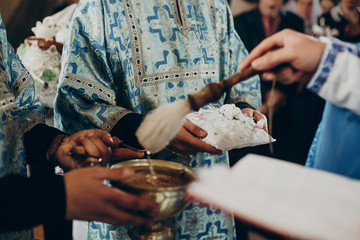 priest blessing wedding rings with holy water for wedding ceremony in church, space for text. religion concept