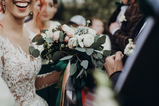 stylish happy bride holding modern bouquet and smiling. emotional moment. rustic wedding morning. space for text. luxury wedding couple and guests.