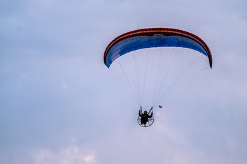 Paraglider flying with paramotor during sunset