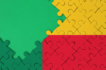 Benin flag  is depicted on a completed jigsaw puzzle with free green copy space on the left side