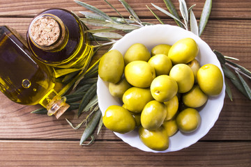 bowl of olives and bottle of extra virgin olive oil on wooden background