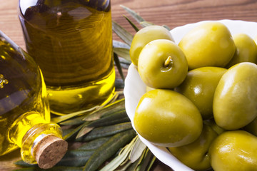 bowl of olives and bottle of extra virgin olive oil on wooden background