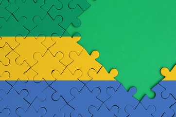 Gabon flag  is depicted on a completed jigsaw puzzle with free green copy space on the right side