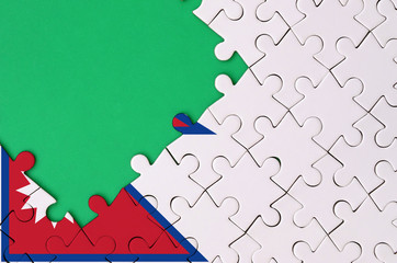 Nepal flag  is depicted on a completed jigsaw puzzle with free green copy space on the left side